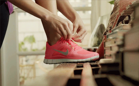 someone tying a purple tennis shoe as they look at an exercise machine