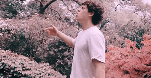 a boy in a white shirt throwing blue flowers in the air