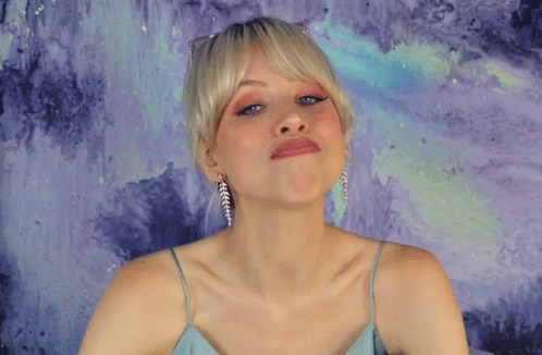 a woman is blue and posing in front of an abstract background