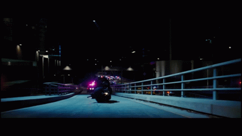a person riding on a motorcycle down a bridge at night