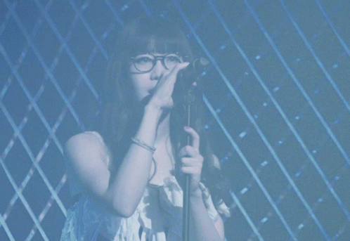 a woman with glasses singing into a microphone