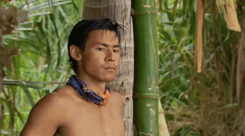 an asian man in blue shirt standing near bamboo pole