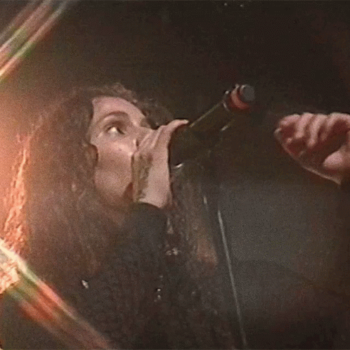 the woman has microphone in her mouth and is singing