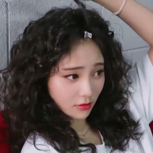 a woman with long hair blow drying her dark curly hair
