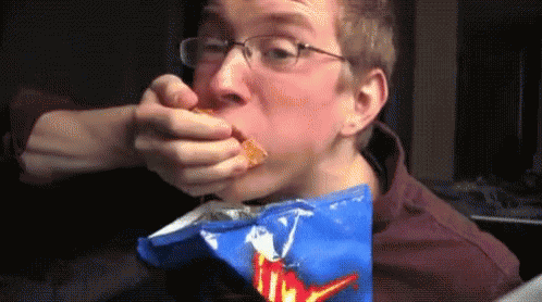 a man eats an orange bag with blue writing on it