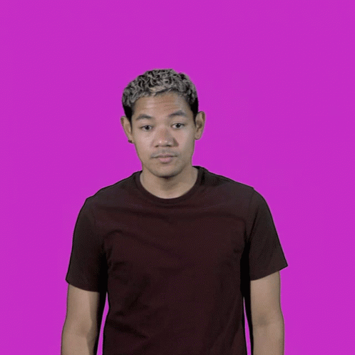 a man standing against a purple background wearing a black shirt