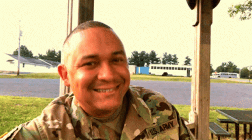 a man wearing camo and smiling at the camera