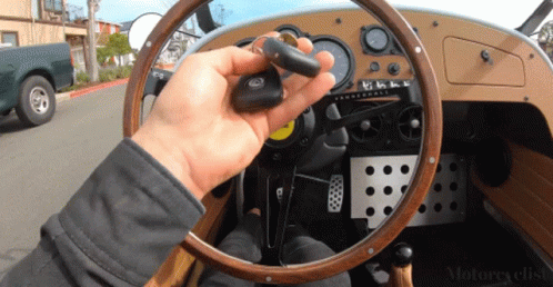 the driver of a blue car holding up a steering wheel