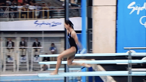 a woman jumps over some large metal bars in a track