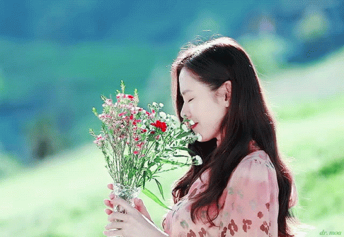 a pretty young woman holding a bouquet of flowers