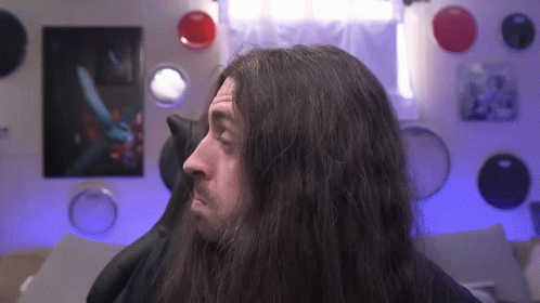 a man with long hair wearing makeup and looking off in to distance