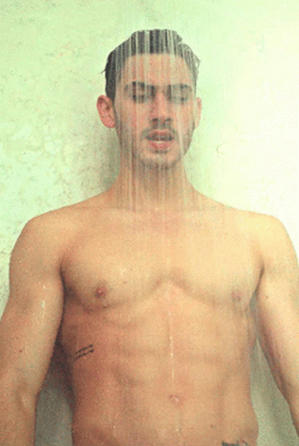 a shirtless man standing in the rain with his head partially covered
