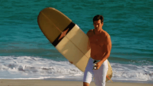 a person with blue hair carrying a surfboard out to the ocean