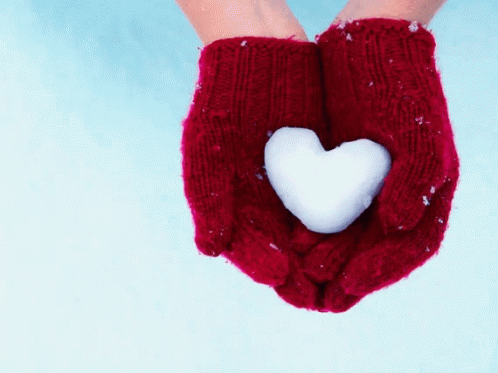 the hand in the knitted mittens has a heart shaped cookie