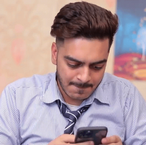 a man with a tie and shirt on looking at his cell phone