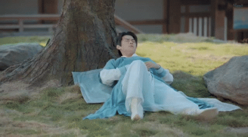 a woman laying under a tree wearing a yellow robe