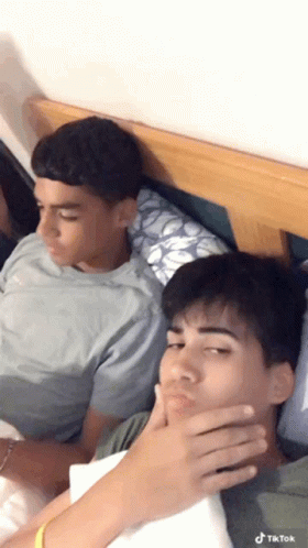 two young men laying down on the same bed