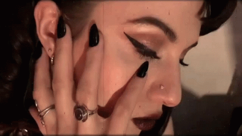 an artistic makeup picture of a female face, nail polish and ring on her fingers