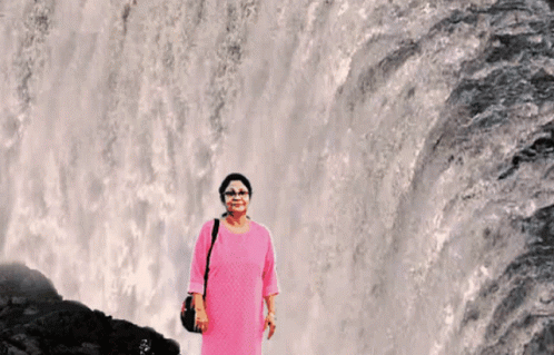 woman wearing purple standing in front of waterfall