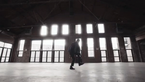 a person walking in an empty room next to a bunch of windows