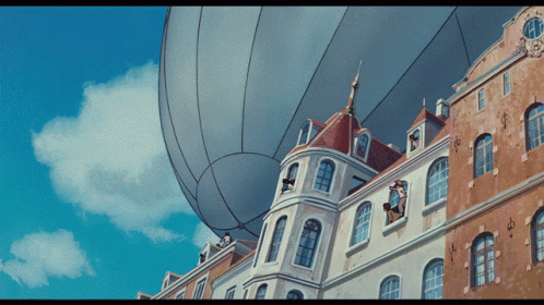 the big balloons are floating over the building