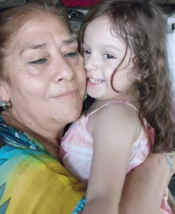 a little girl is holding her grandmother with both hands