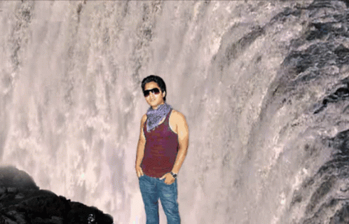 man standing in front of water fall looking like he has the look of avatar