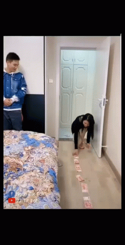 a person looking at the floor while standing near a bed