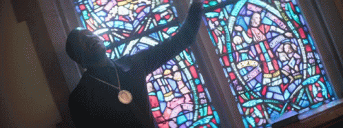 a person in a black shirt and a large stain glass window