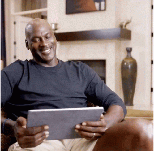 man smiling while holding a tablet on his lap