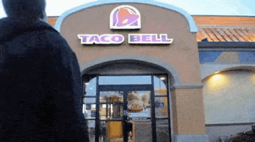 there is a man walking outside a taco bell