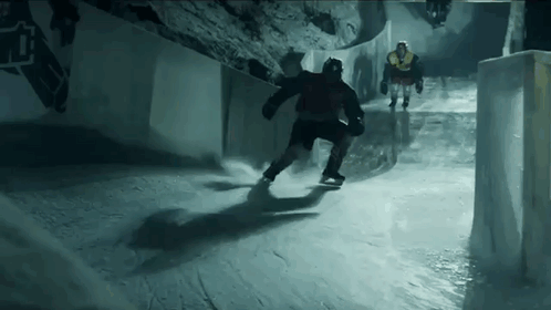 skateboarders ride down a narrow pathway in the dark