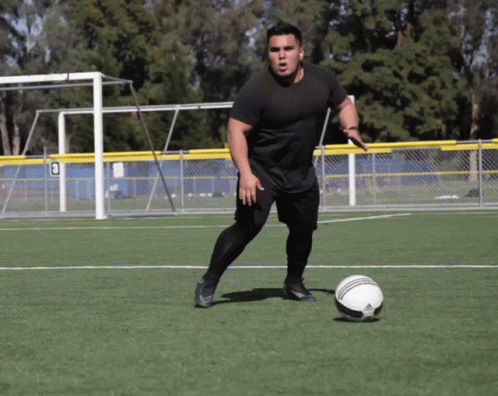 a soccer player is kicking a ball across the field