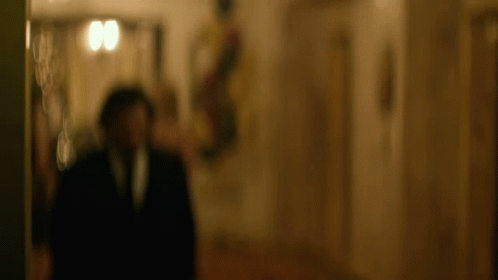 man in black suit walking down hallway of building