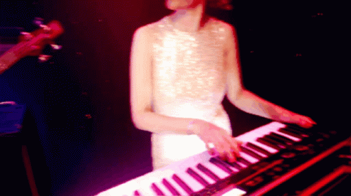 a woman is standing at a keyboard in the dark