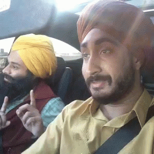 two men are sitting in a car one with a blue turban on