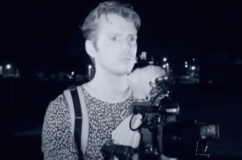 a person standing near a camera with his arm around a camera