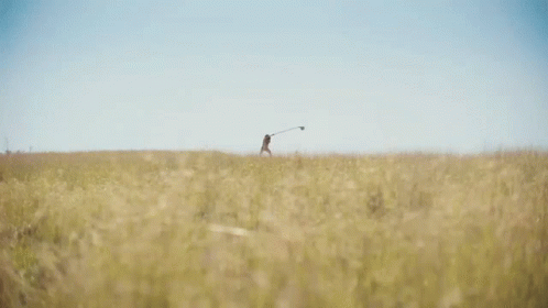 a man with a golf pole is walking through the grass