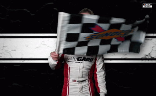a man holding a cheque and racing flag