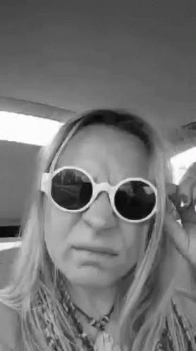 a woman with long hair wearing sunglasses while standing in a car
