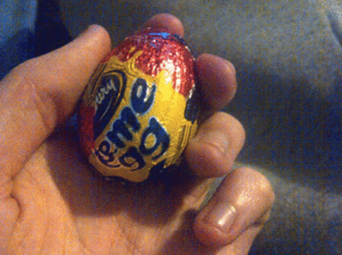 a person holding up a chocolate egg with candy on it