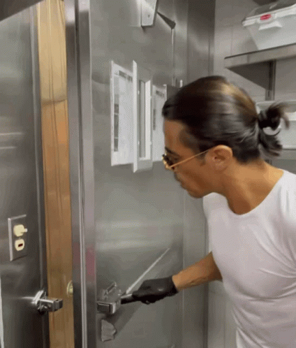 a woman is touching the door to a metallic wall