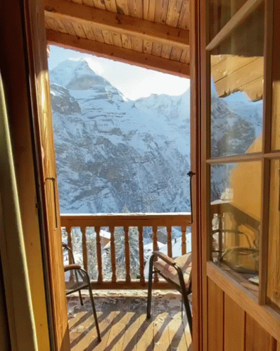 a deck with chairs and mountains seen from the open door