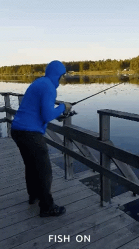 a person in an orange jacket is fishing on a dock