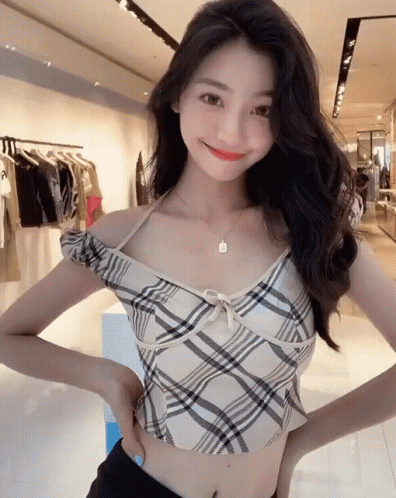 the young woman smiles while wearing a plaid top