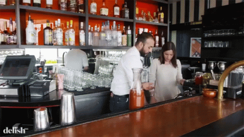 people standing at a bar making drinks