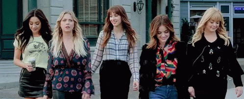 four woman dressed in the same clothes walk in a row on the street