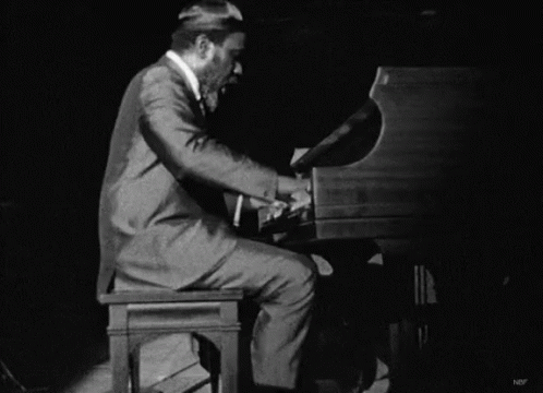 a man wearing a suit plays the piano