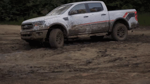 the pickup truck is covered in mud on a muddy road