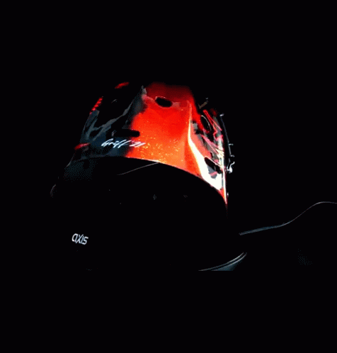 the helmet of a motorcycle rider is lit up against a dark background